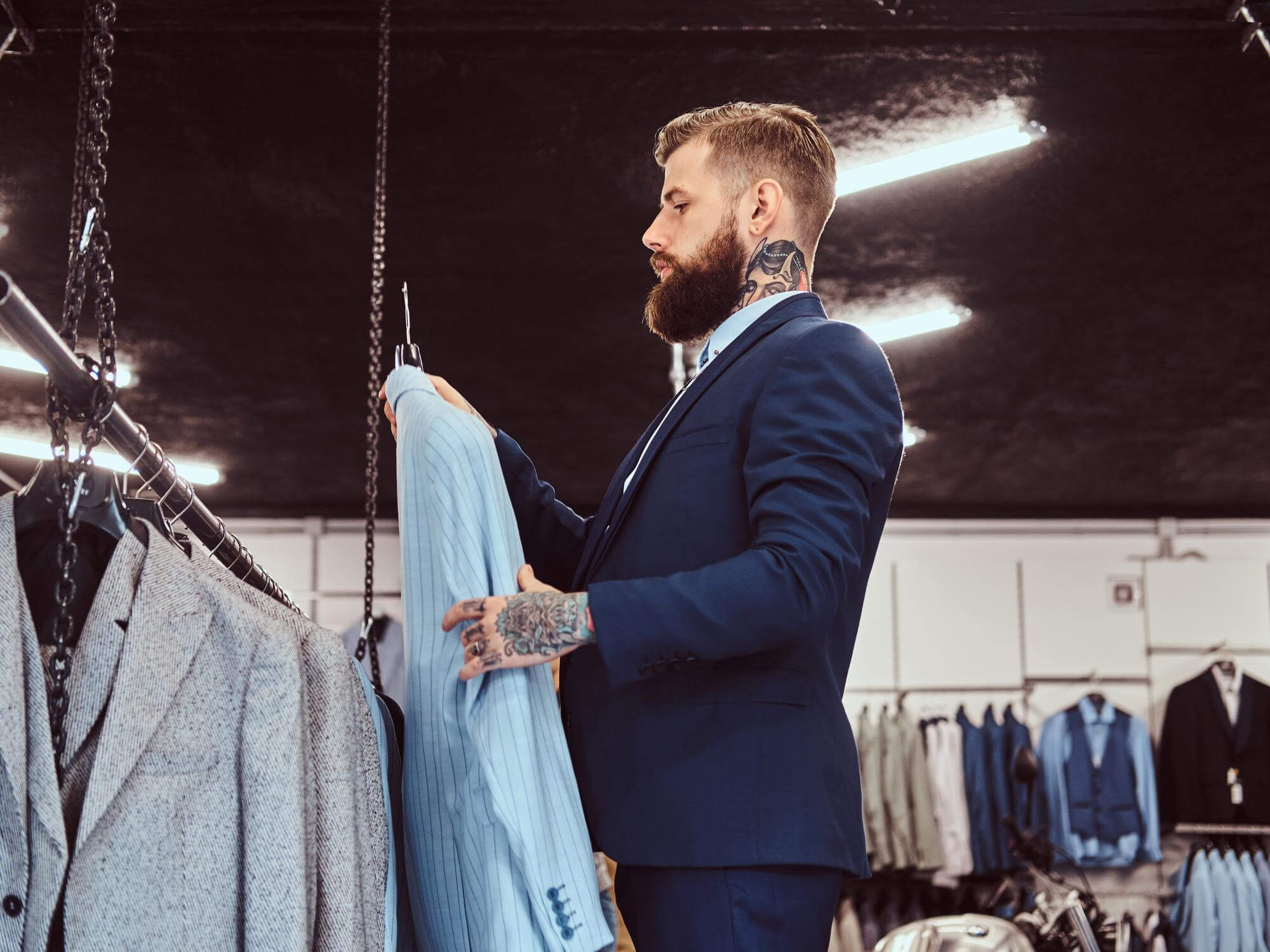 6 elegantly-dressed-bearded-male-with-tattoos-hands-neck-chooses-new-suit-menswear-store
